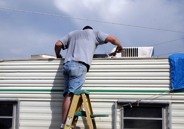 RV technician applying roof sealant to an RV in Port St. Lucie